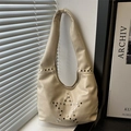 Beige hobo bag with silver star rivets shown in a stylish lifestyle setting - White