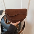 Detail view of a vintage dark brown suede saddle bag with an embossed logo and wide strap - Brown