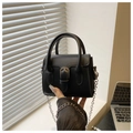Dettaglio mini borsa in pelle nera con fibbia argentata e manico rigido arrotondato - Nero
