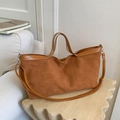 Detail der braunen Vintage Wildleder-Einkaufstasche mit verstellbarem Gurt auf Holztisch - Braun