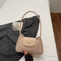 Pink crescent underarm bag with crocodile texture and silver bow detail on white bedding - Khaki