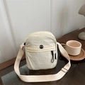 Bolso bandolera minimalista de nailon crema para mujer con logo de moda en mesa madera - Blanco