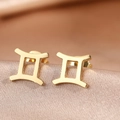 Macro view of gold stainless steel Gemini zodiac earrings on a silk fabric background - Gold Gemini (F1205-Gemini)