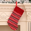 Calza di Natale in maglia rossa e grigia con motivi a fiocco di neve su un caminetto - A Strisce