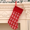 Calza di Natale in maglia rossa con motivi a fiocco di neve bianchi appesa al camino - Albero di Natale