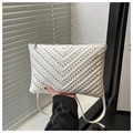 Close-up of white quilted crossbody bag with V-shaped metal studs and zip top closure - White