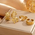 Four gold stainless steel floral and leaf rings set on a textured jewelry box - Gold (C8647)