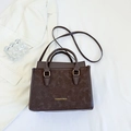 Deep brown leather tote bag with gold lettering and top handles in a stylish office setting - Brown