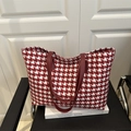 Red and white houndstooth tote bag with leather handles on a white book for daily commute - Red