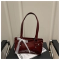 Detail der dunkelroten Lackledertasche mit weißer Spitzenschleife und silbernen Nieten - Rot
