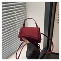 Detalle del mini bolso de ante burdeos con asa redondeada y correa fina al hombro - Rojo