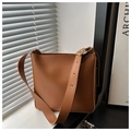 Detailed close-up of brown leather bucket bag with wide strap and gold metal eyelets - Brown