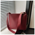 Close-up of deep red leather bucket bag featuring wide eyelet strap and golden buckle - Red