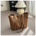 Detail of a brown leather tote bag with gold stamped fashion text on a light gray carpet - Tan