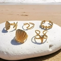 Gedetailleerde weergave van gouden zeesterringen op witte stenen in het zonlicht - Gouden Oceaan Serie Set (C9395)