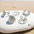 Vijfdelige zilveren zeester en schelp ringenset gepresenteerd op strandrotsen - Zilveren Oceaan Serie Set (C9396)