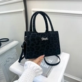 Detailed macro view of black leopard print fabric and metallic YuJin logo on a tote bag - Black