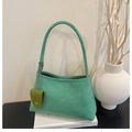 Close-up of mint green suede shoulder bag with olive pendant on minimalist white decor - Green