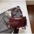 Dettaglio della borsa in pelle verniciata bordeaux con rivetti in metallo e cerniere stile moto - Borgogna