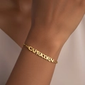 Detail van de 18K vergulde Steenbok naamplaat armband om de pols van het model - Waterman / Goud