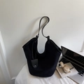 Bolso tote minimalista de ante negro con correas finas y colgante decorativo en un escritorio - Negro