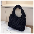 Close-up of the black bubble texture fabric and shoulder strap on a quilted tote bag - Black