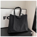 Detail van zwarte shopper met getextureerde stof, lederen handvatten en reliëf merklogo - Zwart