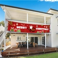 Grande bannière rouge Merry Christmas avec Père Noël suspendue à un balcon de maison blanche - Père Noël / Rouge