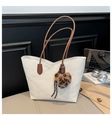 Dettaglio della borsa tote beige con trama litchi, charm cuore leopardato e manici marroni - Con Ciondolo / Bianco