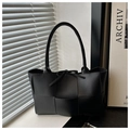 Bolso tote de cuero trenzado negro con detalle de lazo en un entorno de estudio minimalista - Negro