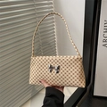 Detailed close-up of beige printed shoulder bag with metallic silver bow decoration - Monogram White