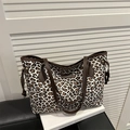 Grande borsa tote leopardata con manici in pelle marrone su una sedia nera - Bianco