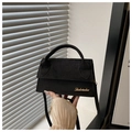 Detail der schwarzen matten Wildledertasche mit goldenem Logo und rundem Griff - Schwarz