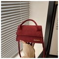 Detail der dunkelroten Wildledertasche mit breitem Griff und goldenem Metalllogo - Rot