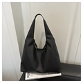 Detail of black pebbled leather tote bag with thick texture on a minimalist sofa - Black