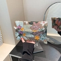 Elegant envelope clutch bag with colorful floral embroidery and sequins held by a model - Brown