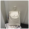 Detail eines cremeweißen Lederrucksacks mit Metallschnalle und Plüschtier auf einem Stuhl - Mit Anhänger / Weiß