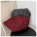 Close-up of wine red matte suede tote bag with knotted handle detail on grey coat background - Red