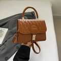 Bolso bandolera acolchado marrón con cierre dorado y emblema de moda en la mano - Marrón