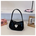 Detail of black crescent handbag featuring a rhinestone heart and golden bow charm - Black