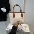 Secchiello chic in pelle color crema e marrone su una valigia per viaggi di stile - Bianco