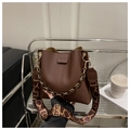 Details einer braunen Leder-Eimertasche mit gemustertem Gurt und goldener Kette - Kaffeebraun