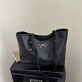 Detail van zwarte kunstlederen shopper met gouden strikaccent en zijdelingse klinknagels - Zwart