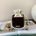 Detail of snake pattern box bag with pearl handle and golden chain on art books - Brown