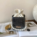 Detail of snake print bucket bag featuring large pearl handle and gold chain strap - Black