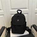 Minimalist black nylon backpack with metal M logo on white background for daily commute - Black