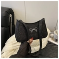 Dettaglio borsa sottobraccio di paillettes nere con fiocco argento su sfondo satinato - Nero