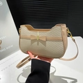 Cream woven handbag with leather bow detail and gold clasp shown in hand - Khaki
