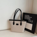 Minimalistische canvas shopper met zwarte lederen bies en handvatten in een studio - Zwart