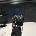 Mini quilted black chain bag with gold floral clasp shown in hand for scale - Black